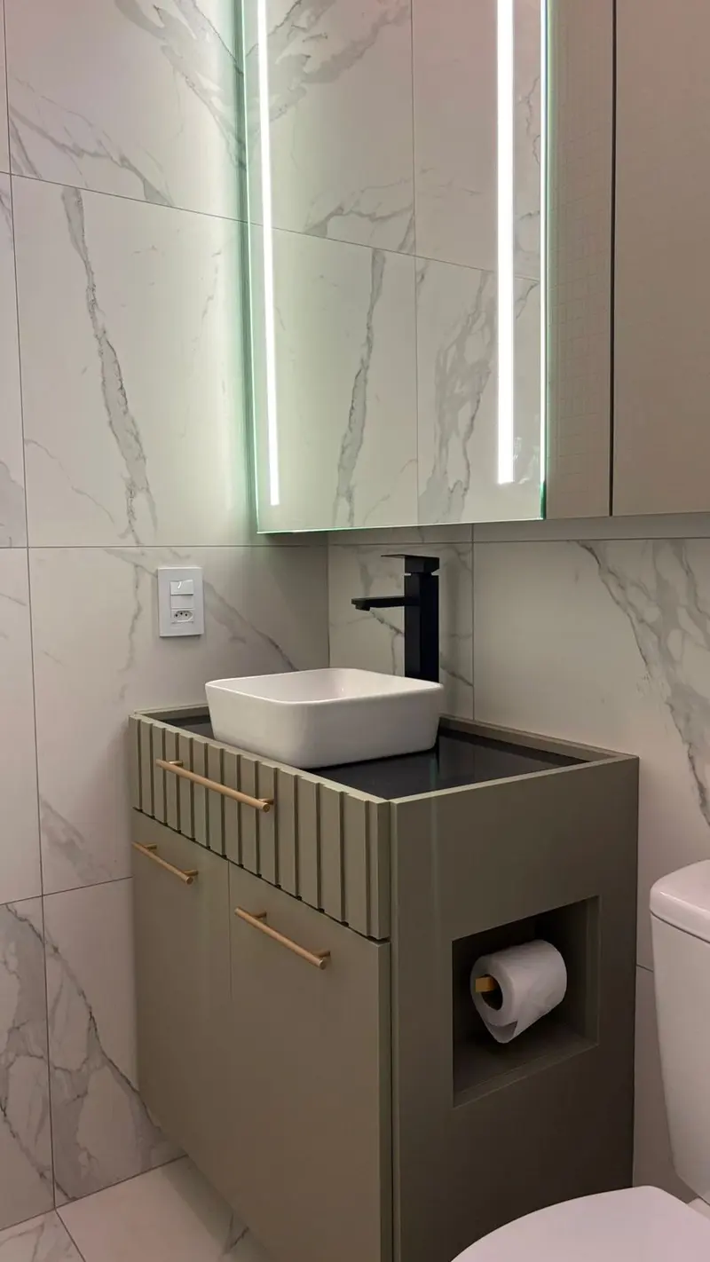 Lavabo com revestimento marmorizado, espelho com LED e gabinete com nicho