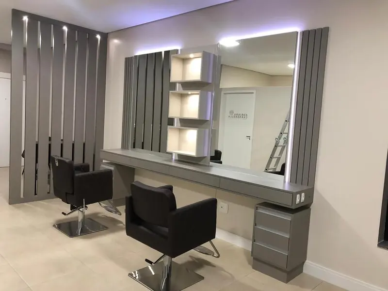 Salão de beleza com bancadas, espelhos iluminados e painel ripado