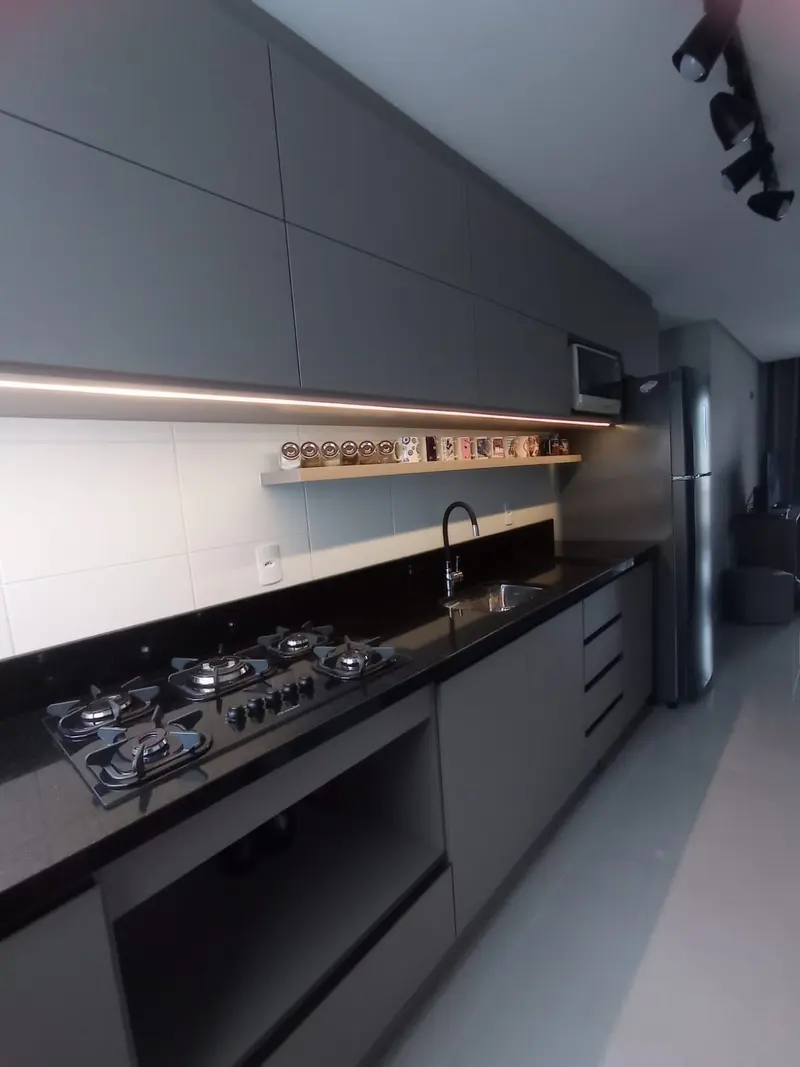 Cozinha linear em cinza com iluminação sob os armários e cooktop embutido