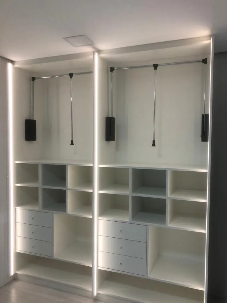 Closet branco com nichos, gavetas e iluminação de LED nas laterais