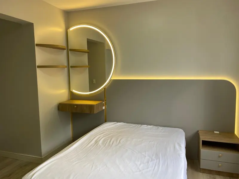 Quarto com cabeceira curva iluminada, nicho e espelho redondo