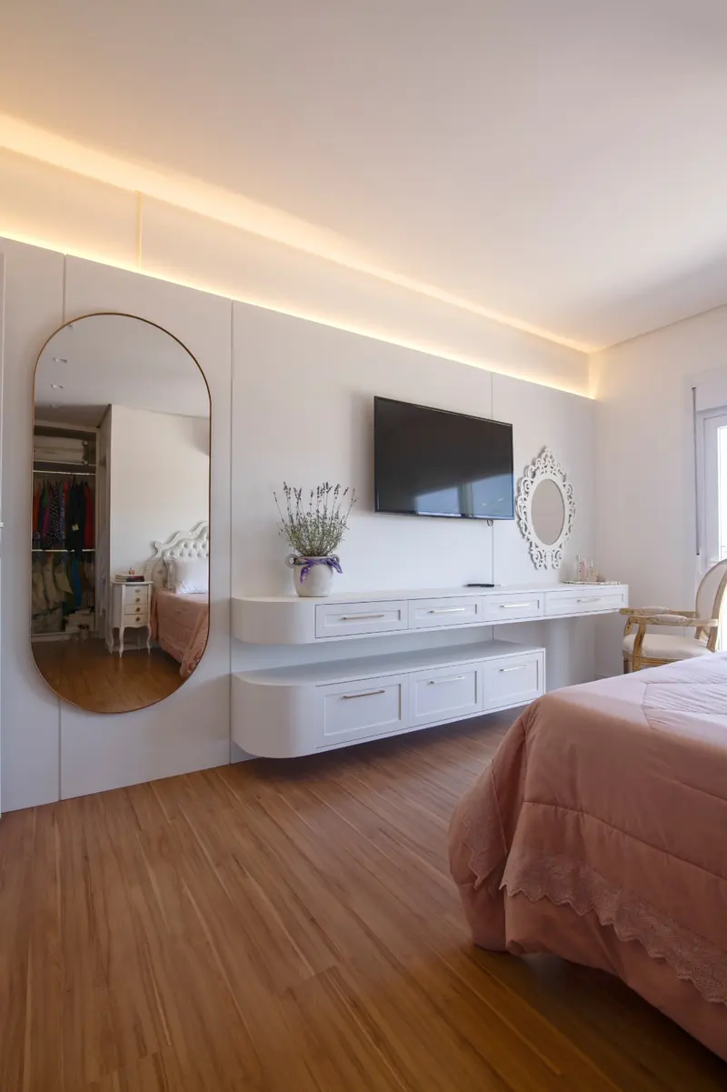 Quarto com penteadeira, espelho oval e painel de TV suspenso