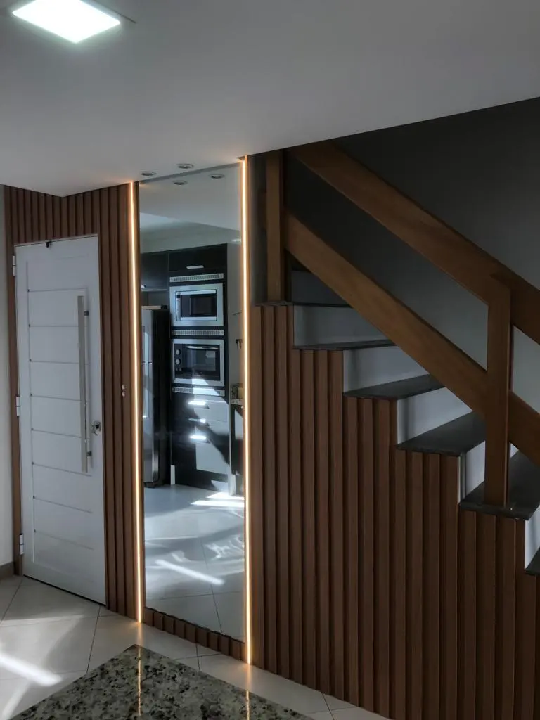 Hall com porta pivotante, ripado de madeira e escada